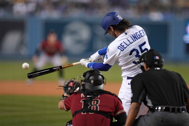 Los Angeles Dodgers center fielder Cody Bellinger follows through on a single in the second inning as Arizona Diamondbacks catcher Carson Kelly (18) watches at Dodger Stadium. Mandatory Credit: Kirby Lee-USA TODAY Sports