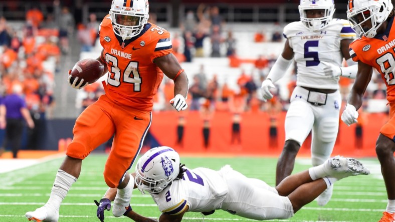 Sep 18, 2021; Syracuse, New York, USA; Syracuse Orange running back Sean Tucker (34) runs with the ball past the tackle attempt of Albany Great Danes defensive back Tyler Carswell (2) during the first half at the Carrier Dome. Mandatory Credit: Rich Barnes-USA TODAY Sports