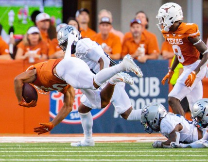 Sep 18, 2021; Austin, Texas; Texas Longhorns running back Bijan Robinson (5) goes airborne after being tripped up by Rice Owl defenders during the first quarter at Darrell K Royal-Texas Memorial Stadium. Mandatory Credit: John Gutierrez-USA TODAY Sports