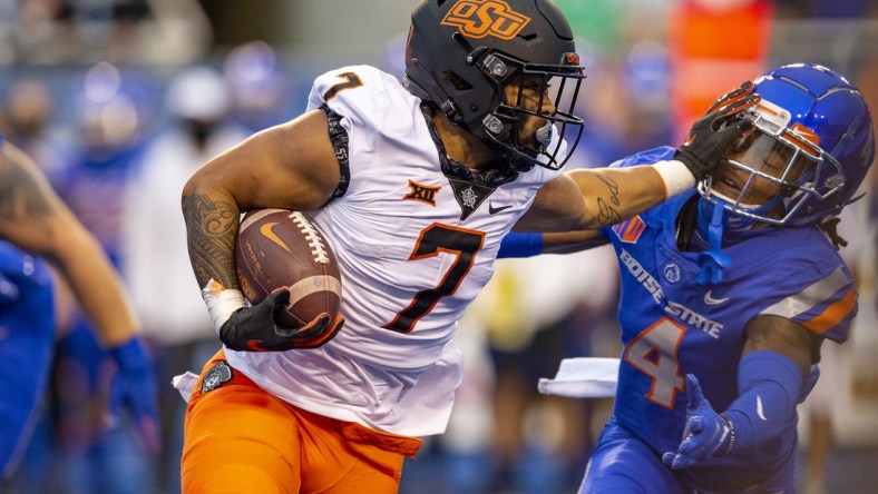 Sep 18, 2021; Boise, Idaho, USA;  Boise State Broncos safety Rodney Robinson (4) gets a stiff arm from Oklahoma State Cowboys running back Jaylen Warren (7) during the first half of play  at Albertsons Stadium. Mandatory Credit: Brian Losness-USA TODAY Sports