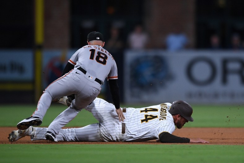 Sep 21, 2021; San Diego, California, USA; San Diego Padres starting pitcher Joe Musgrove (44) is tagged out by San Francisco Giants second baseman Tommy La Stella (18) after being caught in a rundown during the fourth inning at Petco Park. Mandatory Credit: Orlando Ramirez-USA TODAY Sports