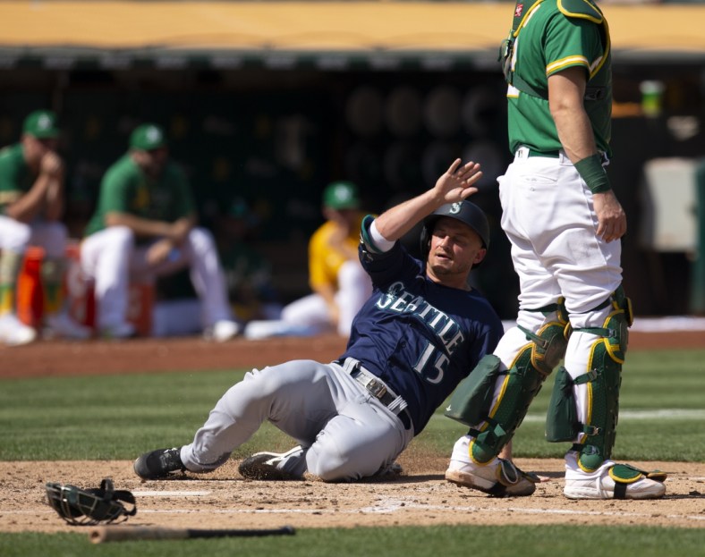 Sep 23, 2021; Oakland, California, USA; Seattle Mariners designated hitter Kyle Seager (15) slides safely home on an RBI double by Abraham Toro during the fourth inning against the Oakland Athletics at RingCentral Coliseum. Mandatory Credit: D. Ross Cameron-USA TODAY Sports