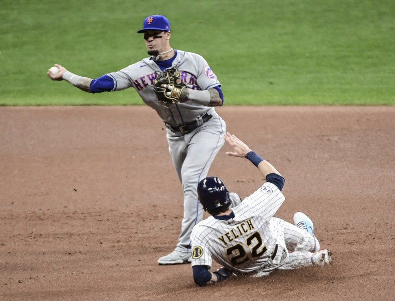 Sep 24, 2021; Milwaukee, Wisconsin, USA; Milwaukee Brewers left fielder Christian Yelich (22) breaks up a double play attempt by New York Mets shortstop Javier Baez (23) in the first inning at American Family Field. Mandatory Credit: Benny Sieu-USA TODAY Sports