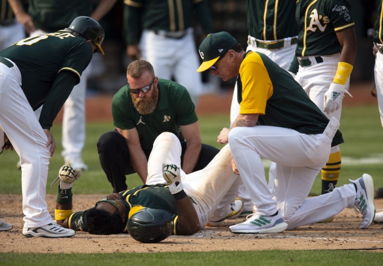 Sep 25, 2021; Oakland, California, USA; Oakland Athletics manager Bob Melvin (right) and a trainer (middle) examine Elvis Andrus after he fell to the ground with an injury while scoring the winning run against the Houston Astros during the ninth inning at RingCentral Coliseum. Mandatory Credit: D. Ross Cameron-USA TODAY Sports