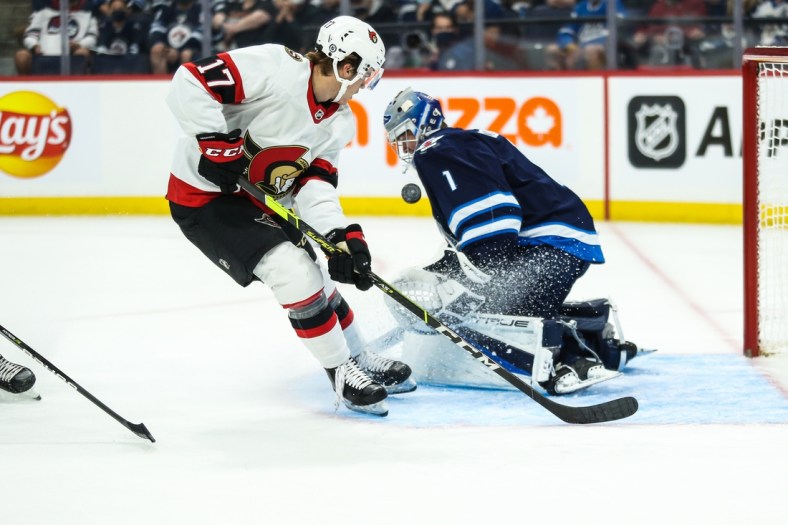Sep 26, 2021; Winnipeg, Manitoba, CAN;  Winnipeg Jets goalie Eric Comrie (1) makes a save on Ottawa Senators forward Ridly Greig (17) during the first period at Canada Life Centre. Mandatory Credit: Terrence Lee-USA TODAY Sports