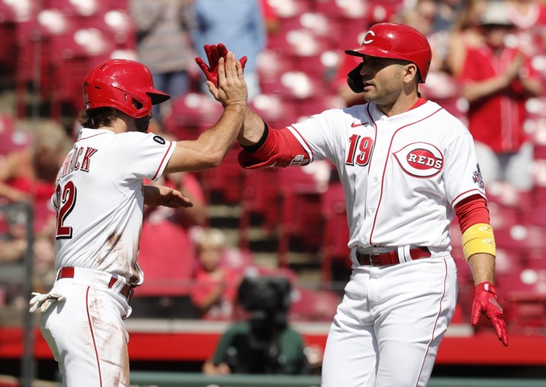 Sep 27, 2021; Cincinnati, Ohio, USA; Cincinnati Reds first baseman Joey Votto (19) reacts with left fielder Max Schrock (32) after hitting a two-run home run against the Pittsburgh Pirates during the first inning at Great American Ball Park. Mandatory Credit: David Kohl-USA TODAY Sports