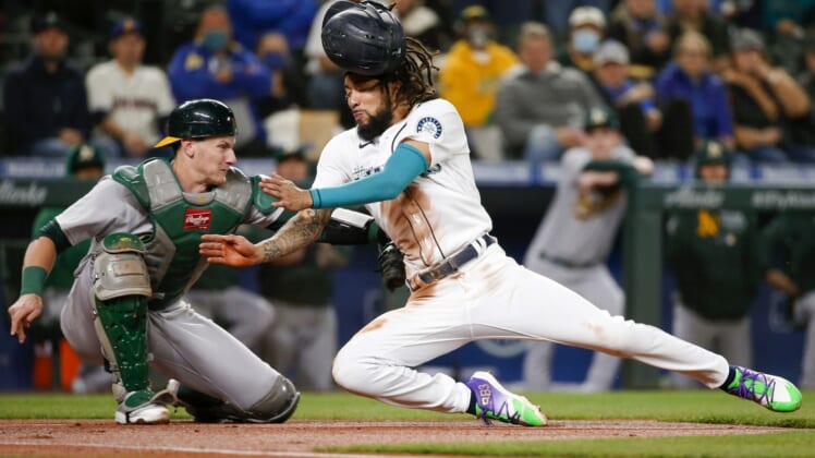 Sep 28, 2021; Seattle, Washington, USA; Oakland Athletics catcher Sean Murphy (12) tags out Seattle Mariners shortstop J.P. Crawford (right) as Crawford attempts to score from third base on a sacrifice fly during the first inning at T-Mobile Park. Mandatory Credit: Joe Nicholson-USA TODAY Sports