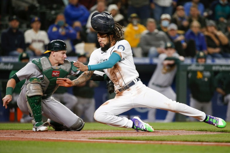 Sep 28, 2021; Seattle, Washington, USA; Oakland Athletics catcher Sean Murphy (12) tags out Seattle Mariners shortstop J.P. Crawford (right) as Crawford attempts to score from third base on a sacrifice fly during the first inning at T-Mobile Park. Mandatory Credit: Joe Nicholson-USA TODAY Sports