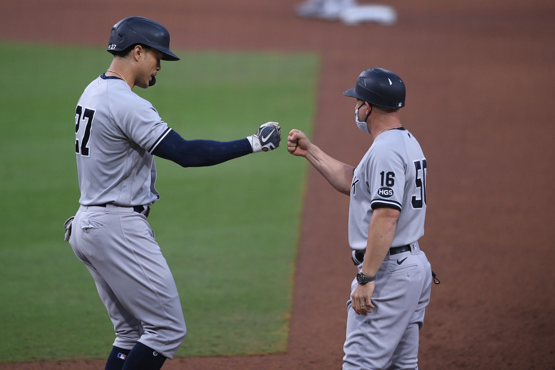 Oct 9, 2020; San Diego, California, USA; New York Yankees designated hitter Giancarlo Stanton (27) fist bumps first base coach Reggie Willits (50) after drawing a walk against the Tampa Bay Rays during the sixth inning of game five of the 2020 ALDS at Petco Park. Mandatory Credit: Orlando Ramirez-USA TODAY Sports