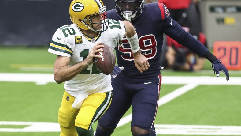 Oct 25, 2020; Houston, Texas, USA; Green Bay Packers quarterback Aaron Rodgers (12) scrambles with the ball as Houston Texans outside linebacker Whitney Mercilus (59) defends during the first quarter at NRG Stadium. Mandatory Credit: Troy Taormina-USA TODAY Sports