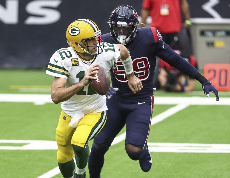 Oct 25, 2020; Houston, Texas, USA; Green Bay Packers quarterback Aaron Rodgers (12) scrambles with the ball as Houston Texans outside linebacker Whitney Mercilus (59) defends during the first quarter at NRG Stadium. Mandatory Credit: Troy Taormina-USA TODAY Sports