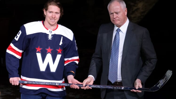 Apr 15, 2021; Washington, District of Columbia, USA; Washington Capitals center Nicklas Backstrom (19) is presented with a silver stick by Capitals' general manager Brian MacClellan (R) during a ceremony in recognition of Backstrom's 1,000th NHL game before the Capitals' game against the Buffalo Sabres at Capital One Arena. Mandatory Credit: Geoff Burke-USA TODAY Sports