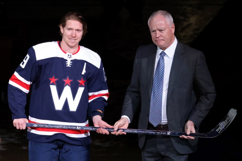 Apr 15, 2021; Washington, District of Columbia, USA; Washington Capitals center Nicklas Backstrom (19) is presented with a silver stick by Capitals' general manager Brian MacClellan (R) during a ceremony in recognition of Backstrom's 1,000th NHL game before the Capitals' game against the Buffalo Sabres at Capital One Arena. Mandatory Credit: Geoff Burke-USA TODAY Sports