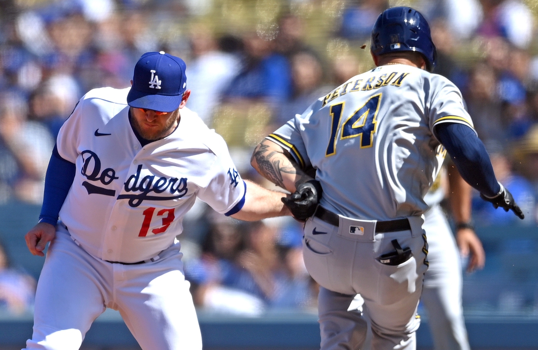 Oct 3, 2021; Los Angeles, California, USA;  Los Angeles Dodgers first baseman Max Muncy (13) injured his left arm as he made a tag on Milwaukee Brewers second baseman Jace Peterson (14) off a throw from Los Angeles Dodgers shortstop Trea Turner (6) in the third inning of the game at Dodger Stadium. Muncy left the game. Mandatory Credit: Jayne Kamin-Oncea-USA TODAY Sports