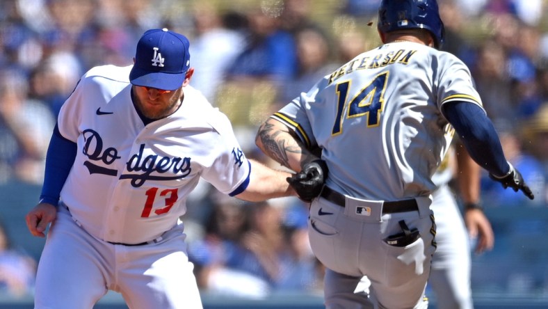 Oct 3, 2021; Los Angeles, California, USA;  Los Angeles Dodgers first baseman Max Muncy (13) injured his left arm as he made a tag on Milwaukee Brewers second baseman Jace Peterson (14) off a throw from Los Angeles Dodgers shortstop Trea Turner (6) in the third inning of the game at Dodger Stadium. Muncy left the game. Mandatory Credit: Jayne Kamin-Oncea-USA TODAY Sports