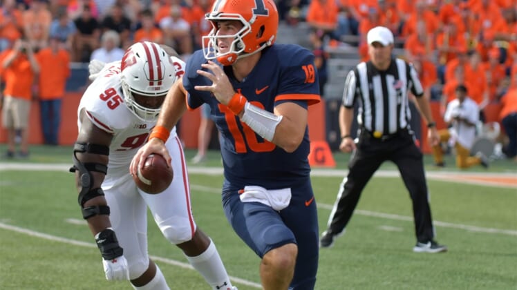 Oct 9, 2021; Champaign, Illinois, USA;  Illinois Fighting Illini quarterback Brandon Peters (18) runs with the ball as Wisconsin Badgers defensive tackle Keeanu Benton (95) pursues in the first half at Memorial Stadium. Mandatory Credit: Ron Johnson-USA TODAY Sports