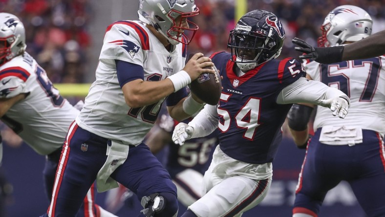 Oct 10, 2021; Houston, Texas, USA; New England Patriots quarterback Mac Jones (10) scrambles with the ball as Houston Texans defensive end Jake Martin (54) defends during the second quarter at NRG Stadium. Mandatory Credit: Troy Taormina-USA TODAY Sports