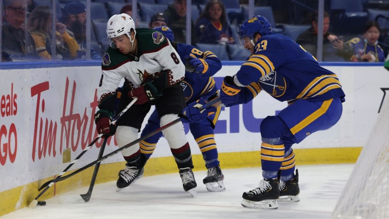 Oct 16, 2021; Buffalo, New York, USA; Arizona Coyotes center Nick Schmaltz (8) and Buffalo Sabres defenseman Colin Miller (33) go after a loose puck along the boards during the first period at KeyBank Center. Mandatory Credit: Timothy T. Ludwig-USA TODAY Sports