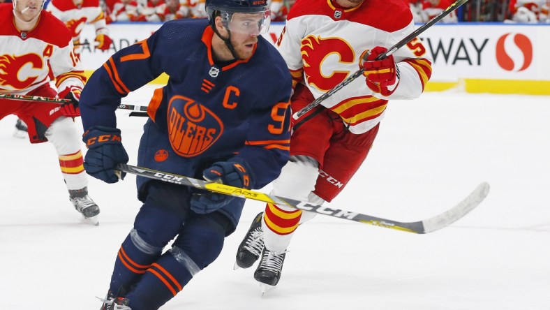 Oct 16, 2021; Edmonton, Alberta, CAN; Edmonton Oilers forward Connor McDavid (97) and Calgary Flames defensemen Noah Hanifin (55) chase a loose puck during the third period at Rogers Place. Mandatory Credit: Perry Nelson-USA TODAY Sports