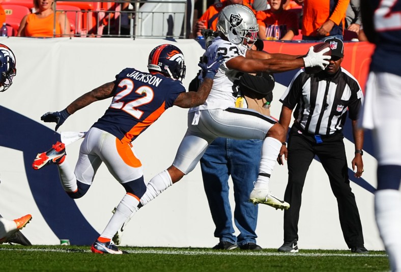 Oct 17, 2021; Denver, Colorado, USA; Las Vegas Raiders running back Kenyan Drake (23) leaps past Denver Broncos safety Kareem Jackson (22) to score a touchdown in the second quarter at Empower Field at Mile High. Mandatory Credit: Ron Chenoy-USA TODAY Sports