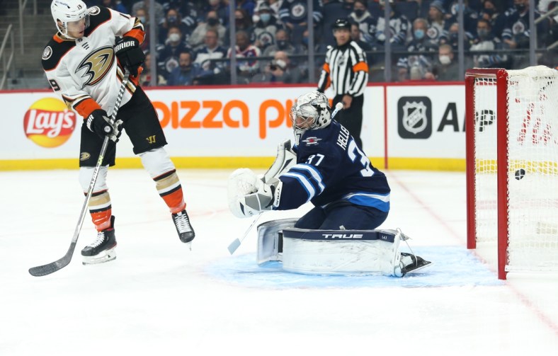 Oct 21, 2021; Winnipeg, Manitoba, CAN;  Anaheim Ducks forward Troy Terry (19) scores on Winnipeg Jets goalie Connor Hellebuyck (37) during the first period at Canada Life Centre. Mandatory Credit: Terrence Lee-USA TODAY Sports