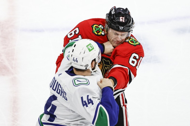 Oct 21, 2021; Chicago, Illinois, USA; Vancouver Canucks defenseman Kyle Burroughs (44) fights with Chicago Blackhawks defenseman Riley Stillman (61) during the first period at United Center. Mandatory Credit: Kamil Krzaczynski-USA TODAY Sports