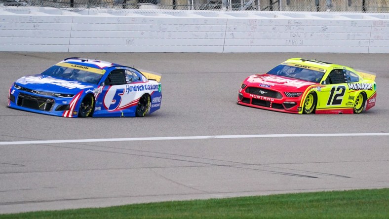 Oct 24, 2021; Kansas City, Kansas, USA; NASCAR Cup Series driver Kyle Larson (5) and driver Ryan Blaney (12) go into turn one near the start of the Hollywood Casino 400 at Kansas Speedway. Mandatory Credit: Denny Medley-USA TODAY Sports