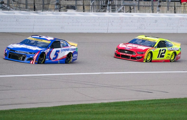 Oct 24, 2021; Kansas City, Kansas, USA; NASCAR Cup Series driver Kyle Larson (5) and driver Ryan Blaney (12) go into turn one near the start of the Hollywood Casino 400 at Kansas Speedway. Mandatory Credit: Denny Medley-USA TODAY Sports