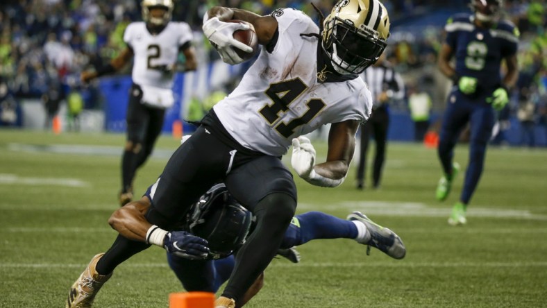 Oct 25, 2021; Seattle, Washington, USA; New Orleans Saints running back Alvin Kamara (41) breaks a tackle by Seattle Seahawks defensive back Ryan Neal (26) to score a touchdown on a reception during the second quarter at Lumen Field. Mandatory Credit: Joe Nicholson-USA TODAY Sports