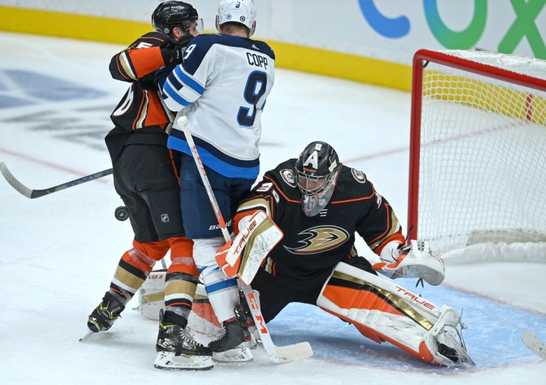 Oct 26, 2021; Anaheim, California, USA;  Anaheim Ducks goaltender John Gibson (36) reaches for the puck as Anaheim Ducks center Trevor Zegras (46) and Winnipeg Jets center Andrew Copp (9) battle for position in front of the net in the second period of the game at Honda Center. Mandatory Credit: Jayne Kamin-Oncea-USA TODAY Sports