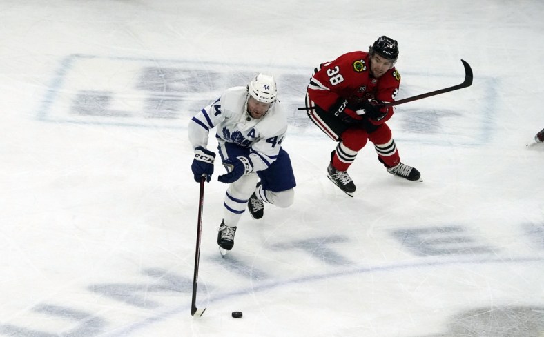 Oct 27, 2021; Chicago, Illinois, USA; Toronto Maple Leafs defenseman Morgan Rielly (44) is defended by Chicago Blackhawks left wing Brandon Hagel (38) during the first period at United Center. Mandatory Credit: David Banks-USA TODAY Sports