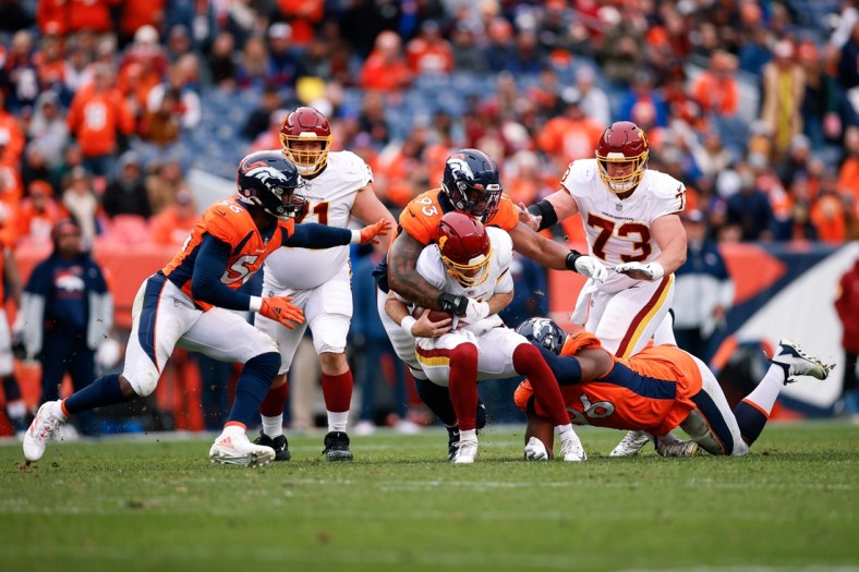 Oct 31, 2021; Denver, Colorado, USA; Washington Football Team quarterback Taylor Heinicke (4) is sacked by Denver Broncos defensive end Shelby Harris (96) and defensive end Dre'Mont Jones (93) as guard Wes Schweitzer (71) and center Chase Roullier (73) and linebacker Baron Browning (56) defend in the second quarter at Empower Field at Mile High. Mandatory Credit: Isaiah J. Downing-USA TODAY Sports