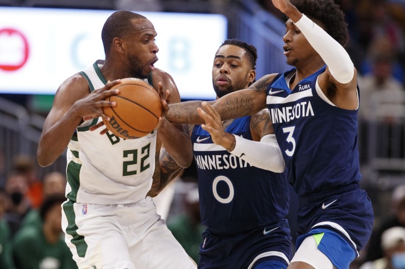 Oct 27, 2021; Milwaukee, Wisconsin, USA;  Milwaukee Bucks forward Khris Middleton (22) tries to keep the ball away from Minnesota Timberwolves forward Jaden McDaniels (3) and guard D'Angelo Russell (0) during the first quarter at Fiserv Forum. Mandatory Credit: Jeff Hanisch-USA TODAY Sports