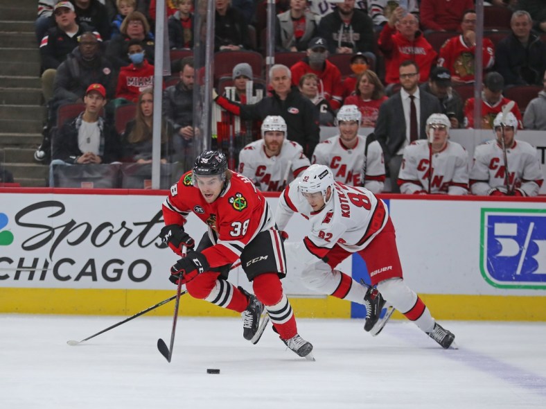 Nov 3, 2021; Chicago, Illinois, USA; Chicago Blackhawks left wing Brandon Hagel (38) and Carolina Hurricanes center Jesperi Kotkaniemi (82) chase the puck during the first period at the United Center. Mandatory Credit: Dennis Wierzbicki-USA TODAY Sports