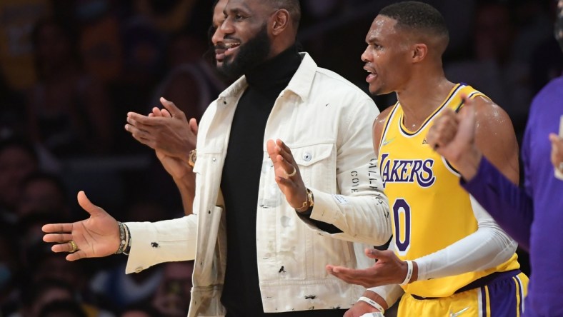 Nov 4, 2021; Los Angeles, California, USA; Los Angeles Lakers forward LeBron James (center) and guard Russell Westbrook (0) look on from the bench during the game against the Oklahoma City Thunder at Staples Center. Mandatory Credit: Jayne Kamin-Oncea-USA TODAY Sports