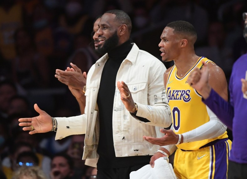 Nov 4, 2021; Los Angeles, California, USA; Los Angeles Lakers forward LeBron James (center) and guard Russell Westbrook (0) look on from the bench during the game against the Oklahoma City Thunder at Staples Center. Mandatory Credit: Jayne Kamin-Oncea-USA TODAY Sports