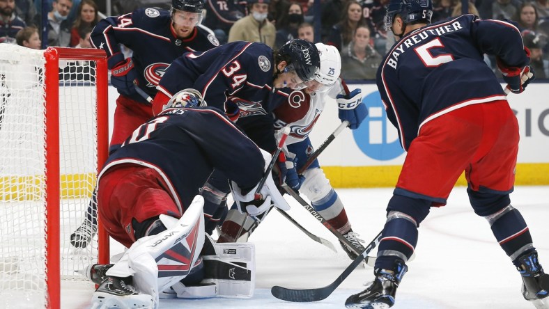 Nov 6, 2021; Columbus, Ohio, USA; Columbus Blue Jackets center Cole Sillinger (34) and Colorado Avalanche right wing Logan O'Connor (25) battle for a loose puck during the third period at Nationwide Arena. Mandatory Credit: Russell LaBounty-USA TODAY Sports