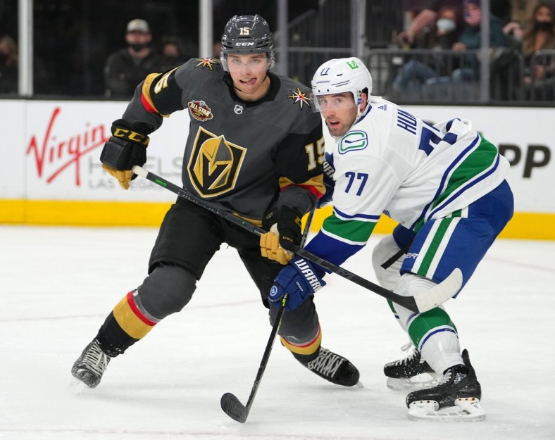 Nov 13, 2021; Las Vegas, Nevada, USA; Vegas Golden Knights center Jake Leschyshyn (15) ties up the stick of Vancouver Canucks defenseman Brad Hunt (77) during the second period at T-Mobile Arena. Mandatory Credit: Stephen R. Sylvanie-USA TODAY Sports
