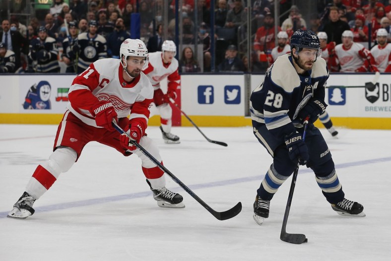 Nov 15, 2021; Columbus, Ohio, USA; Columbus Blue Jackets right wing Oliver Bjorkstrand (28) carries the puck as Detroit Red Wings center Dylan Larkin (71) trails the play during the first period at Nationwide Arena. Mandatory Credit: Russell LaBounty-USA TODAY Sports