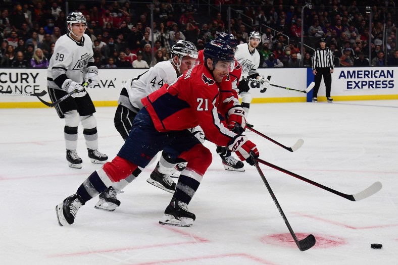 Nov 17, 2021; Los Angeles, California, USA; Washington Capitals right wing Garnet Hathaway (21) moves the puck ahead of Los Angeles Kings defenseman Mikey Anderson (44) during the third period at Staples Center. Mandatory Credit: Gary A. Vasquez-USA TODAY Sports
