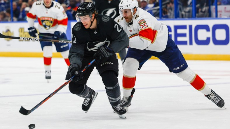 Nov 13, 2021; Tampa, Florida, USA;  Tampa Bay Lightning center Brayden Point (21) controls the puck past Florida Panthers defenseman Aaron Ekblad (5) in the second period at Amalie Arena. Mandatory Credit: Nathan Ray Seebeck-USA TODAY Sports