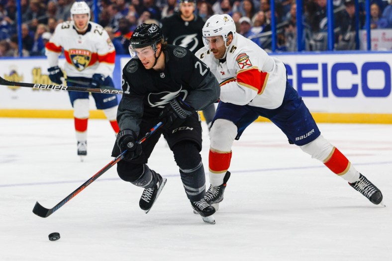 Nov 13, 2021; Tampa, Florida, USA;  Tampa Bay Lightning center Brayden Point (21) controls the puck past Florida Panthers defenseman Aaron Ekblad (5) in the second period at Amalie Arena. Mandatory Credit: Nathan Ray Seebeck-USA TODAY Sports