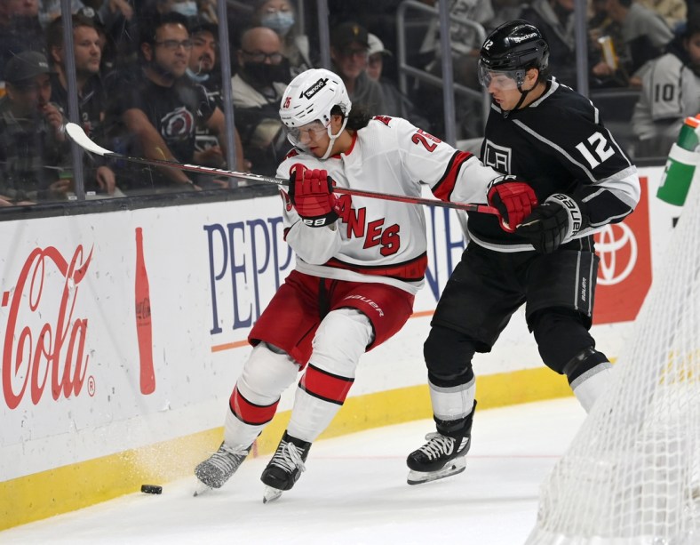 Nov 20, 2021; Los Angeles, California, USA;  Carolina Hurricanes defenseman Ethan Bear (25) and Los Angeles Kings center Trevor Moore (12) battle for the puck in the second period at Staples Center. Mandatory Credit: Jayne Kamin-Oncea-USA TODAY Sports
