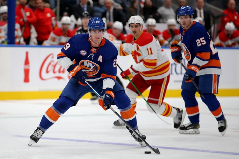 Nov 20, 2021; Elmont, New York, USA; New York Islanders center Brock Nelson (29) skates with the puck in front of Calgary Flames center Mikael Backlund (11) and Islanders defenseman Sebastian Aho (25) during the second period at UBS Arena. Mandatory Credit: Brad Penner-USA TODAY Sports