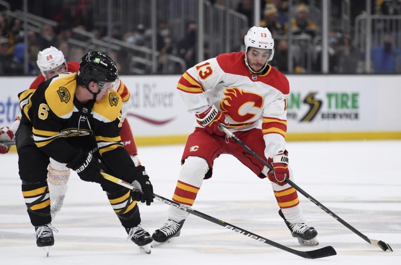Nov 21, 2021; Boston, Massachusetts, USA;  Calgary Flames left wing Johnny Gaudreau (13) controls the puck while Boston Bruins defenseman Mike Reilly (6) defends during the second period at TD Garden. Mandatory Credit: Bob DeChiara-USA TODAY Sports