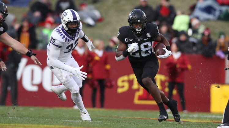 Nov 26, 2021; Ames, Iowa, USA; Iowa State Cyclones running back Breece Hall (28) runs away from TCU Horned Frogs defensive end Ochaun Mathis (32) at Jack Trice Stadium. Mandatory Credit: Reese Strickland-USA TODAY Sports