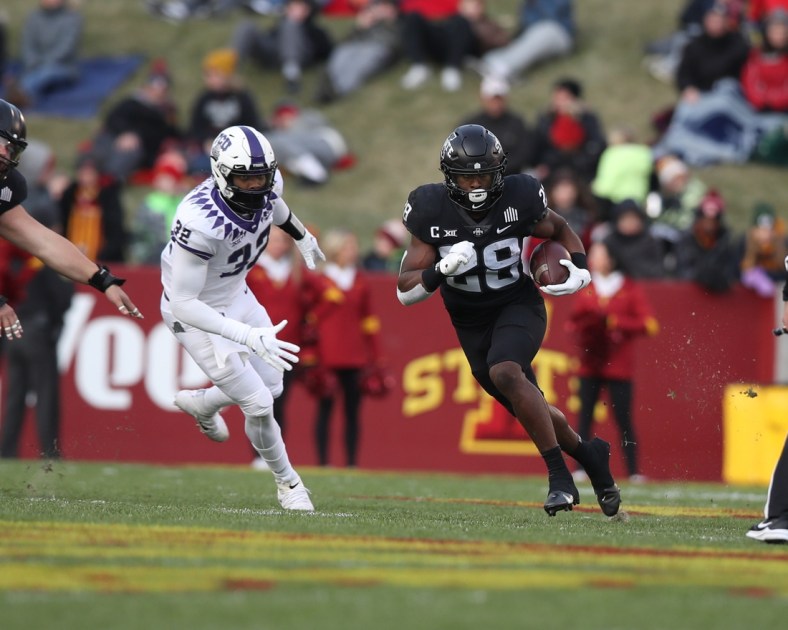 Nov 26, 2021; Ames, Iowa, USA; Iowa State Cyclones running back Breece Hall (28) runs away from TCU Horned Frogs defensive end Ochaun Mathis (32) at Jack Trice Stadium. Mandatory Credit: Reese Strickland-USA TODAY Sports