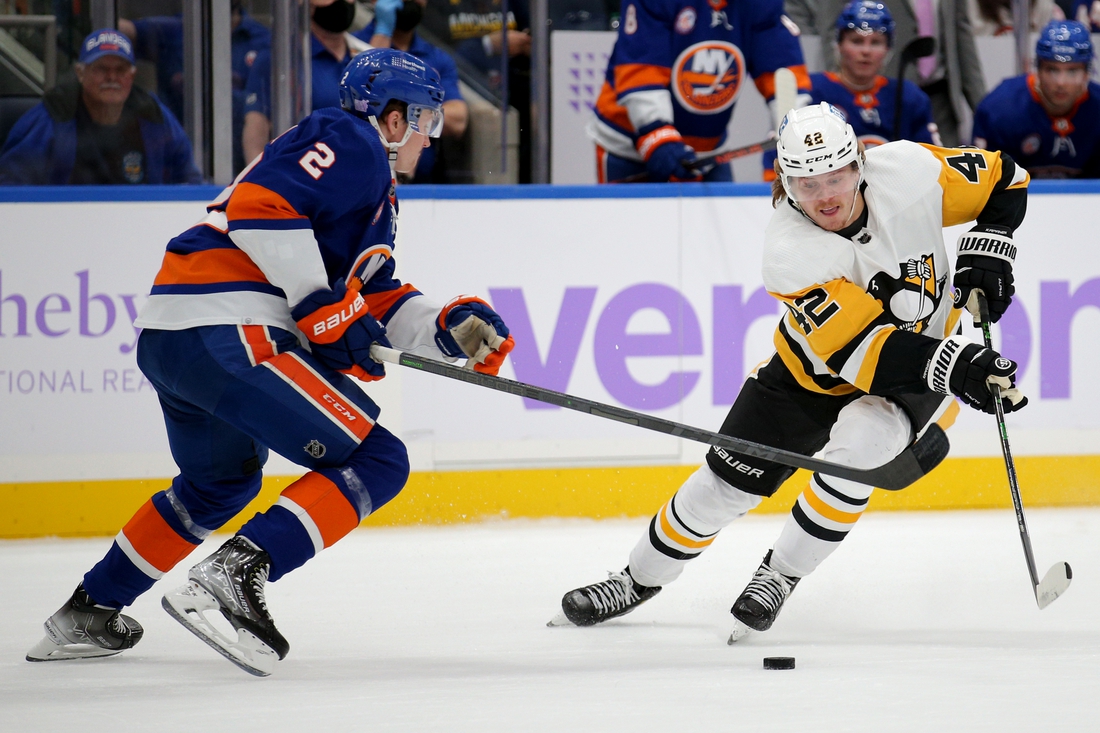 Nov 26, 2021; Elmont, New York, USA; Pittsburgh Penguins right wing Kasperi Kapanen (42) plays the puck against New York Islanders defenseman Robin Salo (2) during the first period at UBS Arena. Mandatory Credit: Brad Penner-USA TODAY Sports