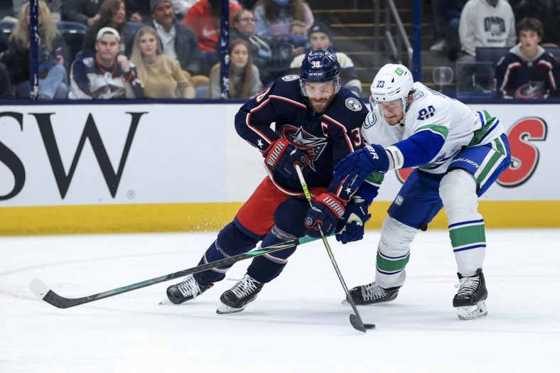 Nov 26, 2021; Columbus, Ohio, USA; Columbus Blue Jackets center Boone Jenner (38) skates against Vancouver Canucks defenseman Oliver Ekman-Larsson (23) in the second period at Nationwide Arena. Mandatory Credit: Aaron Doster-USA TODAY Sports