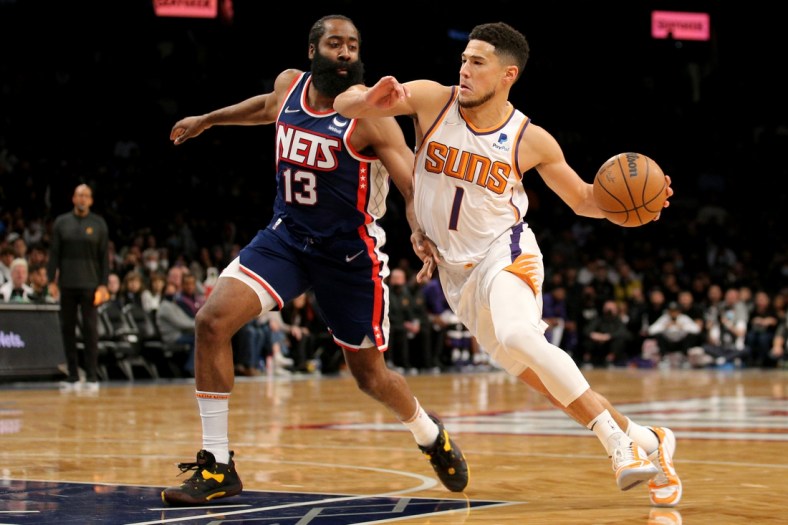 Nov 27, 2021; Brooklyn, New York, USA; Phoenix Suns guard Devin Booker (1) drives to the basket around Brooklyn Nets guard James Harden (13) during the first quarter at Barclays Center. Mandatory Credit: Brad Penner-USA TODAY Sports